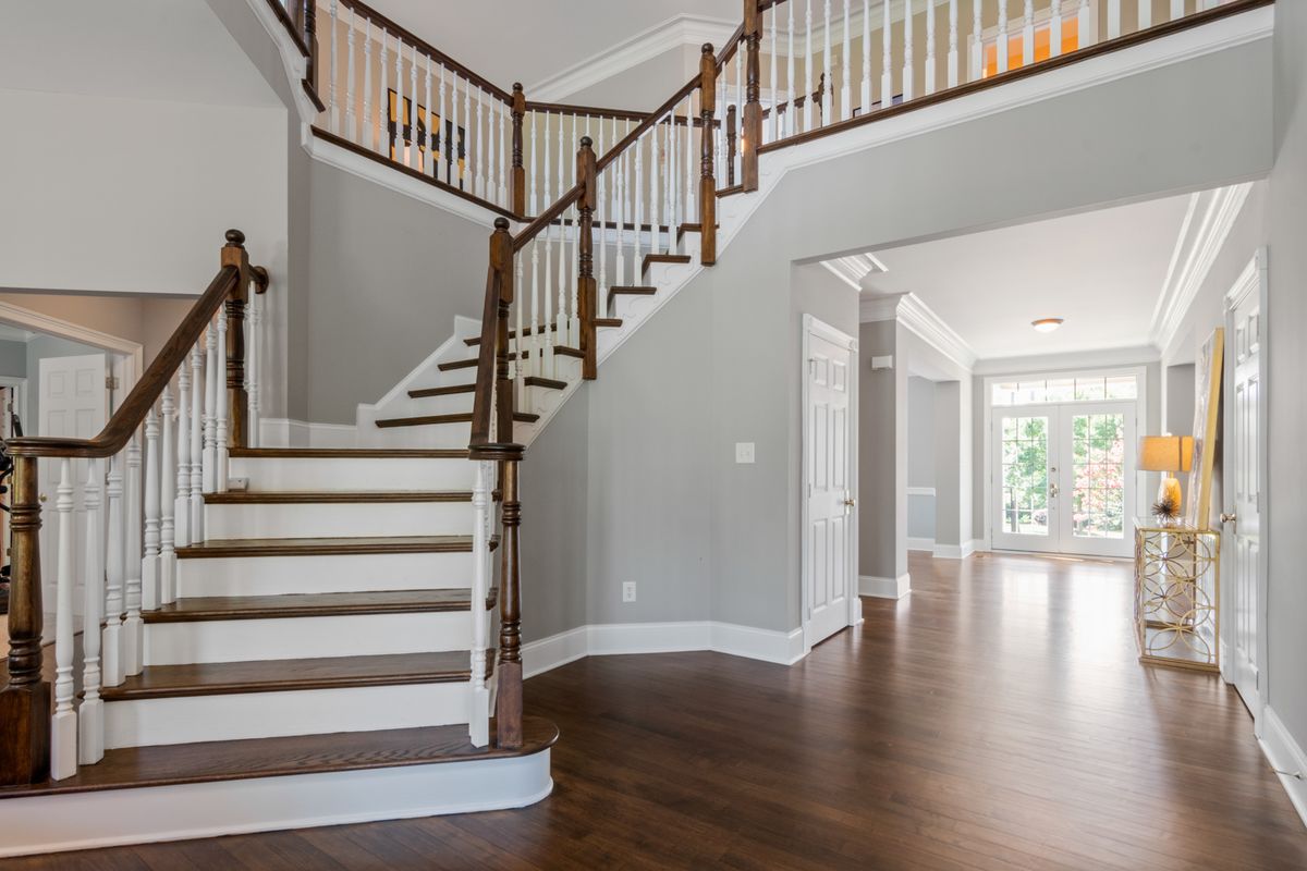 Intérieur lumineux d'une maison à étage avec escalier et grande hauteur sous plafond